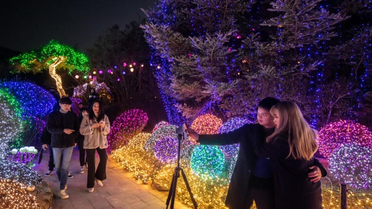 In a photo taken on January 11, 2020 visitors take a selfie as they look at an annual light display at the 'Garden on Morning Calm', near Gapyeong, east of Seoul. Ed JONES / AFP