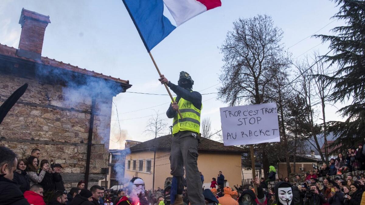 Masked revellers - one wearing a yellow vest waving a French national flag - another with a placard which reads as " enough is enough" take part with others in a carnival procession through the south-western North Macedonian village of Vevcani, on January 13, 2020. The Vevcani carnival is 1.400 years old and is held every year on the eve of the feast of Saint Basil (January 14), which also marks the beginning of the New Year according to the Julian calendar, observed by the Macedonian Orthodox Church. Rober
