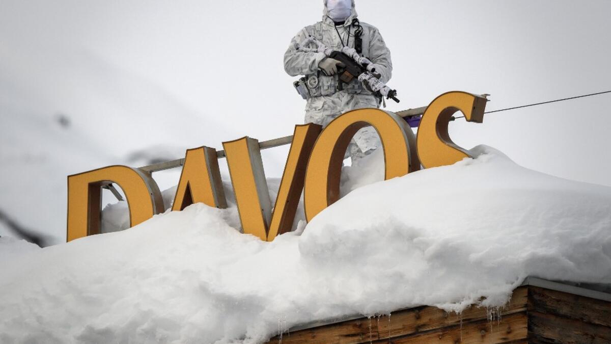 In this file photo taken on January 21, 2019, policeman wearing camouflage clothing stands on the rooftop of a hotel, next to letters covered in snow reading 'Davos', near the Congress Centre ahead of the World Economic Forum (WEF) annual meeting in Davos, eastern Switzerland. The World Economic Forum 50th Annual Meeting in Davos is held from January 21 to 24, 2020. Fabrice COFFRINI / AFP