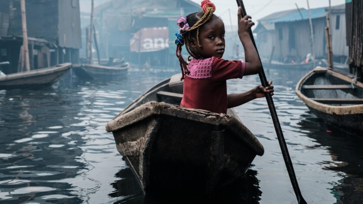 A picture taken on March 1, 2019 shows a girl steering a boat on a waterway in the Makoko waterfront community in a polluted lagoon in Lagos, Africa’s biggest megalopolis in Nigeria. The sprawling community began in the 19th century as a fishing village for immigrants who settled on the water's edge. As more arrived and land became rare, people started to move out onto the water. Over time, Makoko became a floating realm of perhaps a quarter of a million people, although the real number is anyone's guess. Y
