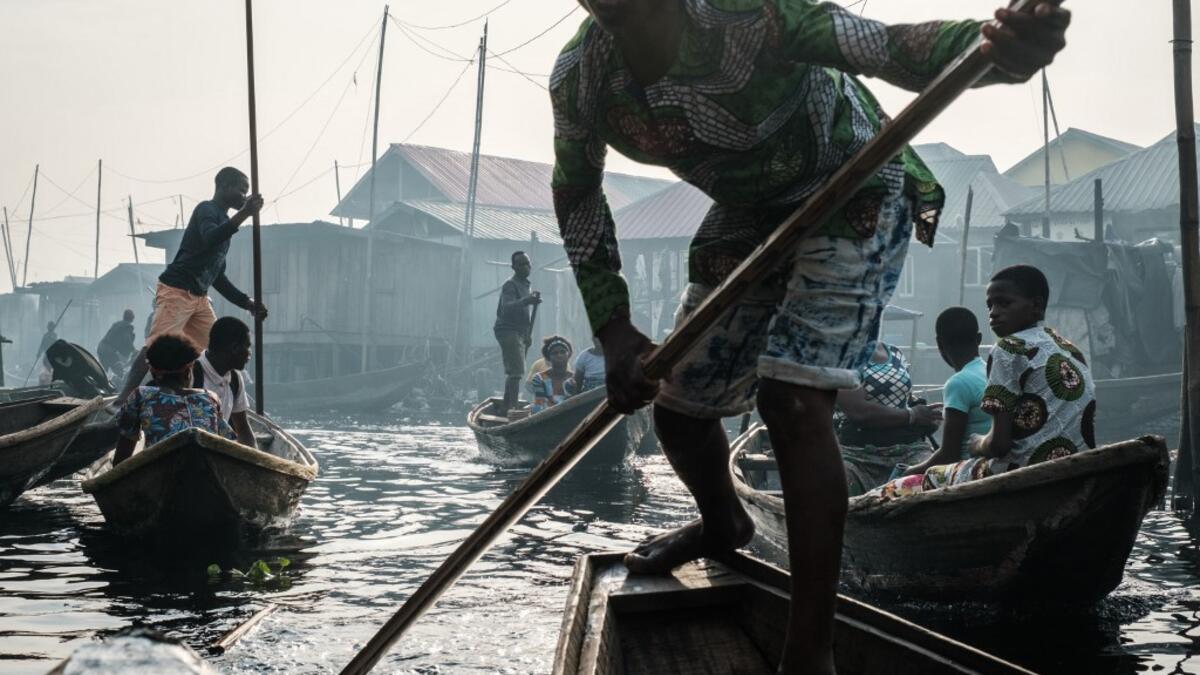 A picture taken on March 2, 2019 shows people steering boats on a waterway in the Makoko waterfront community in a polluted lagoon in Lagos, Africa’s biggest megalopolis in Nigeria. The sprawling community began in the 19th century as a fishing village for immigrants who settled on the water's edge. As more arrived and land became rare, people started to move out onto the water. Over time, Makoko became a floating realm of perhaps a quarter of a million people, although the real number is anyone's guess. YA