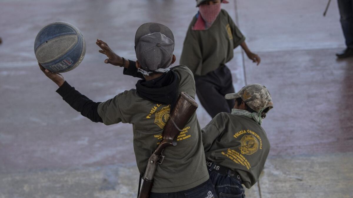 Children play basketball during a break as they are tought to use weapons by the Regional Coordinator of Community Authorities (CRAC-PF) community police force at a basketball court in the village of Ayahualtempan, Guerrero State, Mexico, on January 24, 2020. The CRAC-PF vigilante group trains children as young as five so they can protect themselves from drug-related criminal groups operating in the area. Pedro PARDO / AFP