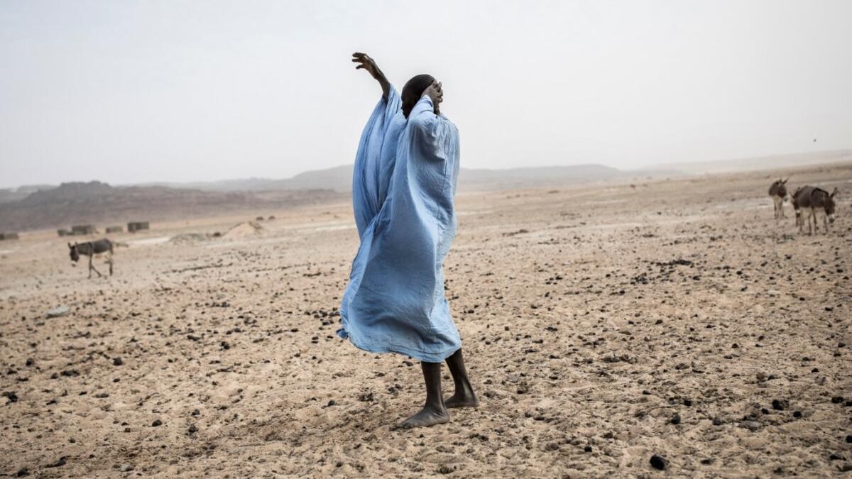 A man gestures to his family at the Touijinit Camp along the caravan route from Tichitt to Aratane in Mauritania on January 25, 2020. In the arid West African country of Mauritania, the way of life of the traditional group of hunters known as the Nemadi is slowly disappearing. JOHN WESSELS / AFP