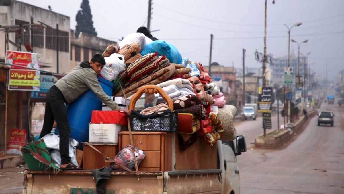 A Syrian youth climbs atop belongings in the back of a truck as people leave the town of Binnish in the northwestern province of Idlib, on February 4, 2020, amid an ongoing offensive by pro-regime forces. A Russian-backed Syrian government offensive against the country's last rebel enclave of Idlib has displaced more than half a million people in two months, according to the United Nations. The wave of displacement, which coincides with a biting winter, is one of the largest since the start of the Syrian wa