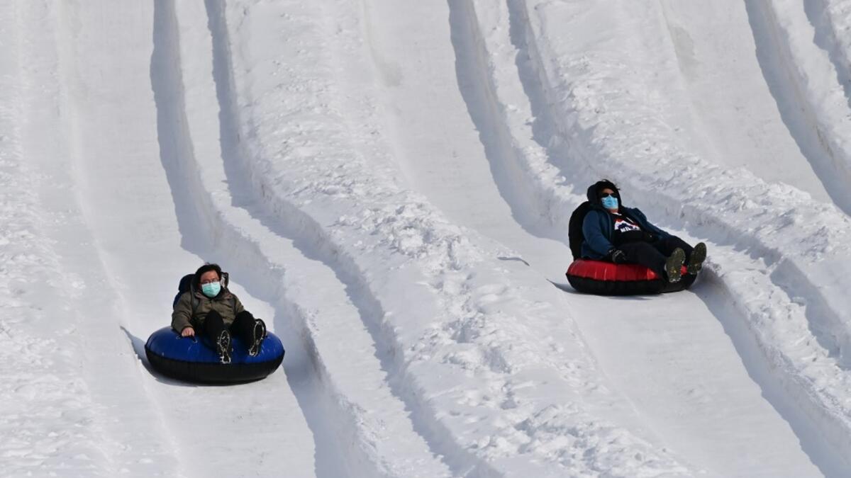 People take part in snow rafting during the Sapporo Snow Festival in Sapporo on February 5, 2020. Organisers for this year's festival were forced to truck in an unprecedented amount of extra powder to build their signature sculptures after an unseasonably warm winter. CHARLY TRIBALLEAU / AFP