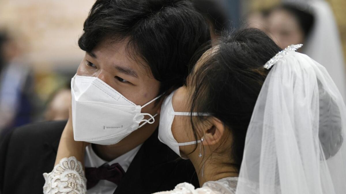 A couple wearing protective face masks attend a mass wedding ceremony organised by the Unification Church at Cheongshim Peace World Center in Gapyeong on February 7, 2020. South Korea has confirmed 24 cases of the SARS-like virus so far and placed nearly 260 people in quarantine for detailed checks amid growing public alarm. Jung Yeon-je / AFP