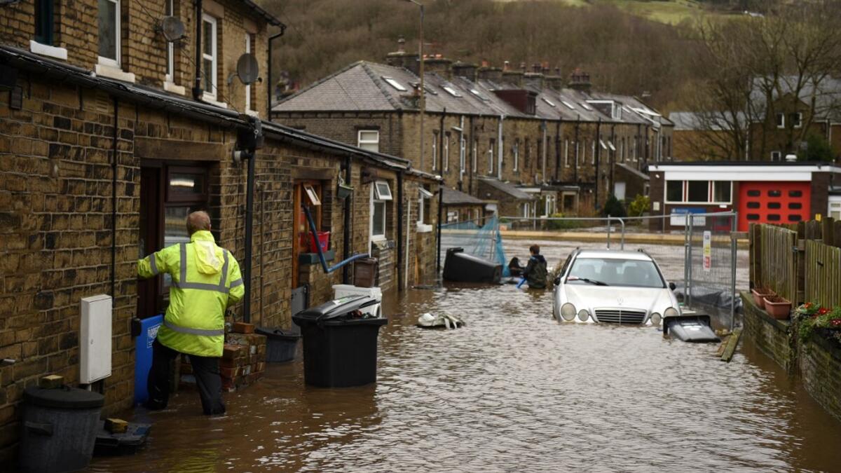 A man enters a house on a flooded street in Mytholmroyd, northern England, on February 9, 2020, after the River Calder burst its banks as Storm Ciara swept over the country. Britain and Ireland hunkered down Sunday for a powerful storm expected to disrupt air, rail and sea links, cancel sports events, cut electrical power and damage property. With howling winds and driving rain, forecasters said Ciara would also hit France, Belgium, the Netherlands, Switzerland and Germany. Oli SCARFF / AFP