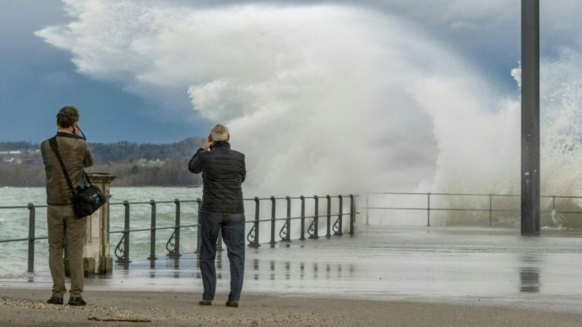 Two men take pictures of water spilling over a quay in the Eastern end of Lake Constance (Bodensee), as the storm Ciara reaches Austria, in Bregenz, Austria, on February 10, 2020. DIETMAR STIPLOVSEK / APA / AFP