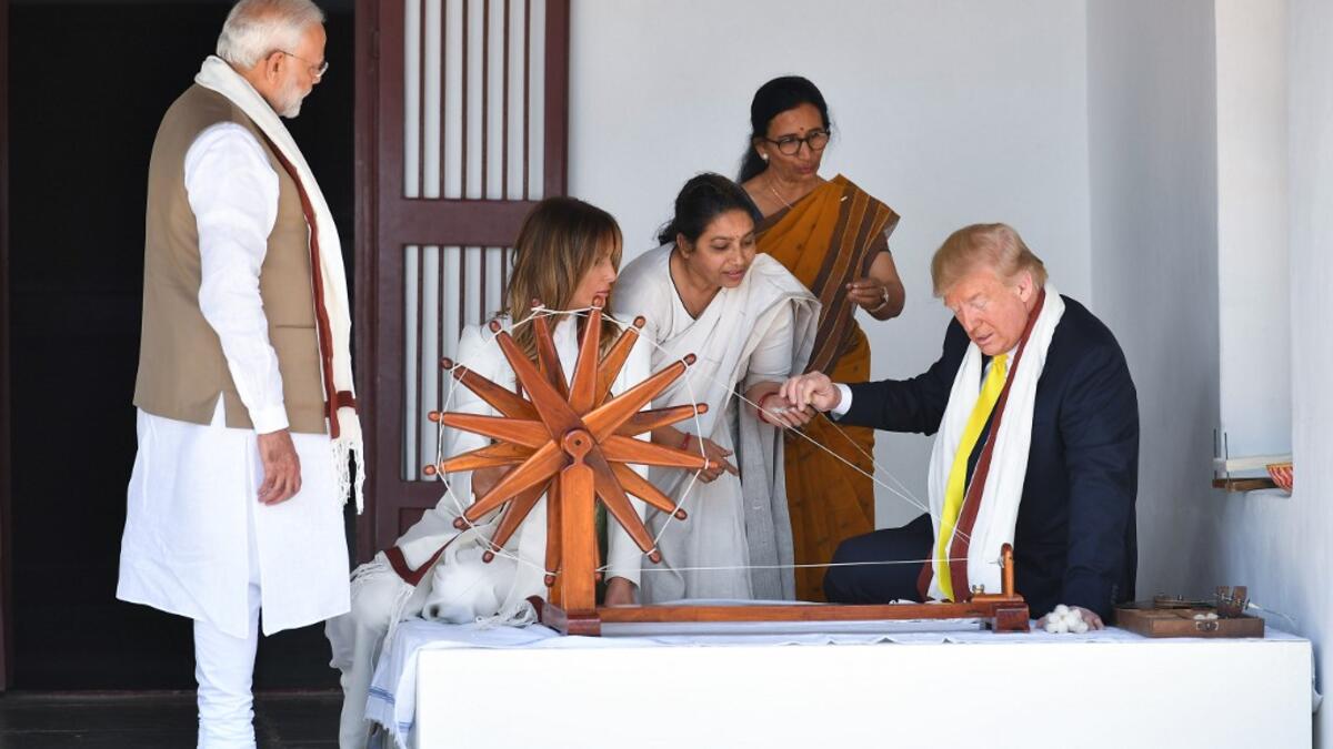 US President Donald Trump (R) holds a string while checking a charkha, or spinning wheel, as First Lady Melania Trump (2L) and India's Prime Minister Narendra Modi (L) look on during their visit at the Gandhi Ashram in Ahmedabad on February 24, 2020. Mandel NGAN / AFP