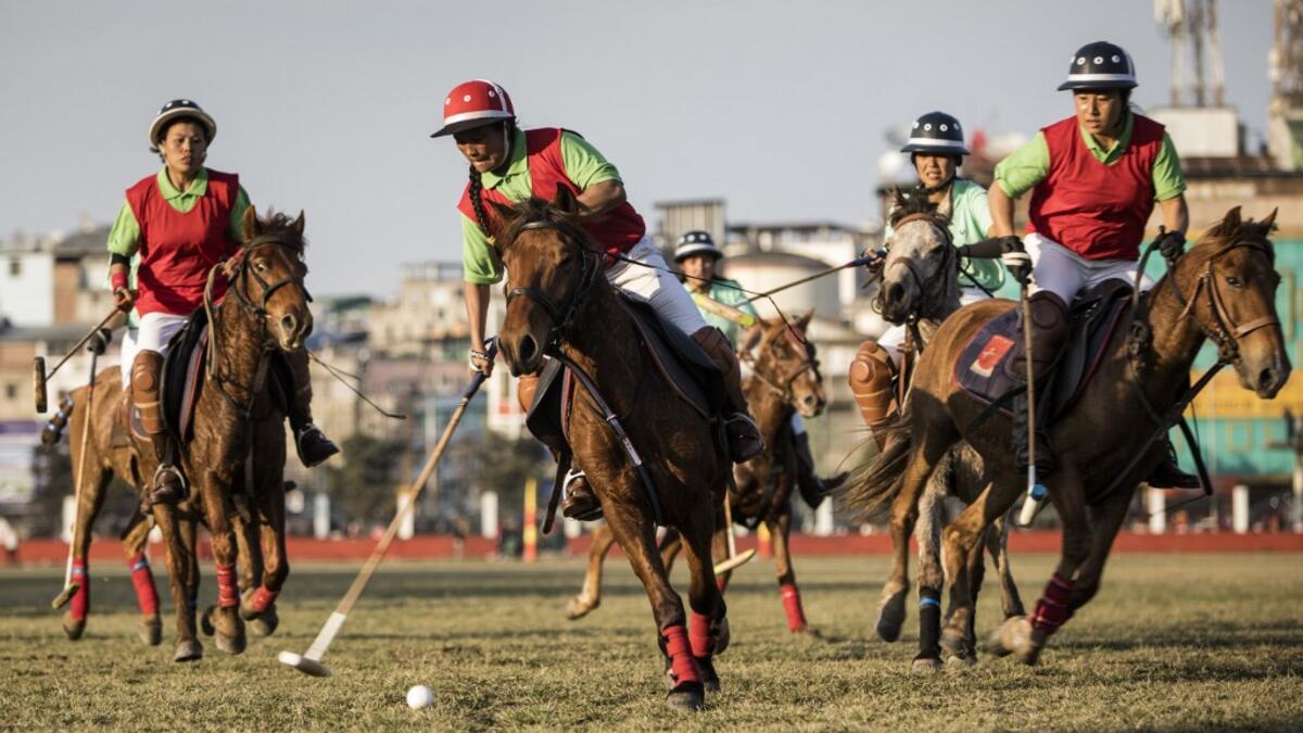 In this photograph taken on January 7, 2020, Linthoingambi Kangjei Lup Polo Club player Khundongbam Dementy (C) shoots to score during their 15th Women's State Polo Tournament match against Chingkheihunba Polo Club at the Mapal Kangjeibung (Polo Ground) in Imphal, the capital of the northeastern Indian state of Manipur. Laishram Thadoi's face is a picture of concentration as she adjusts her helmet and prepares to play in Manipur, the remote Indian state regarded as the birthplace of modern polo. Xavier GALI
