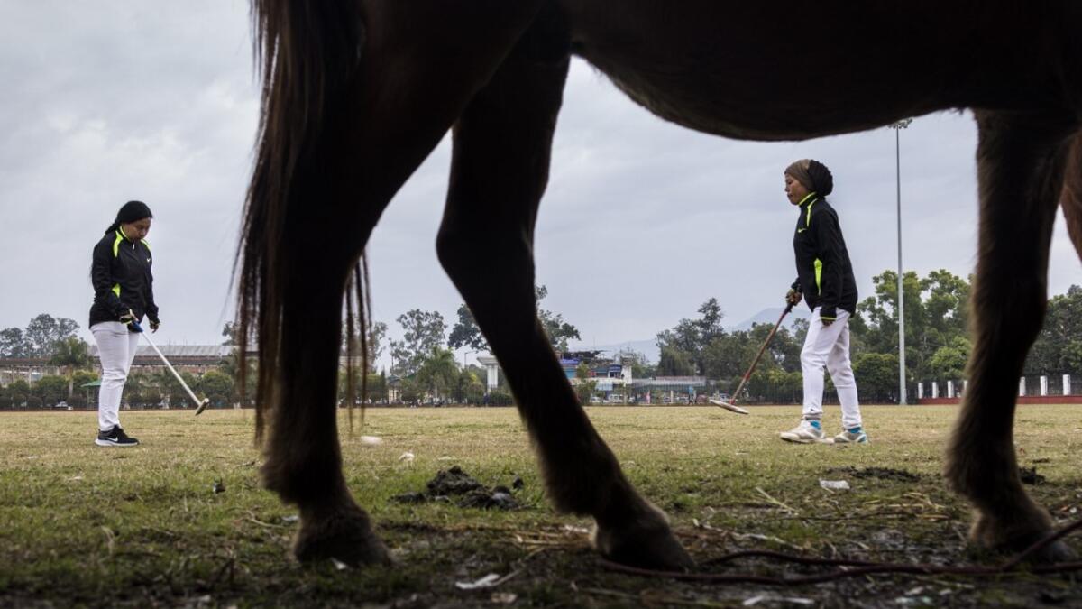 In this photograph taken on January 9, 2020, Linthoingambi Kangjei Lup Polo Club players Shanglenmayum Sangeeta (R) and Okram Ashalucky warm up before the start of their 15th Women's State Polo Tournament match at the Mapal Kangjeibung (Polo Ground) in Imphal, the capital of the northeastern Indian state of Manipur. Laishram Thadoi's face is a picture of concentration as she adjusts her helmet and prepares to play in Manipur, the remote Indian state regarded as the birthplace of modern polo. Xavier GALIANA