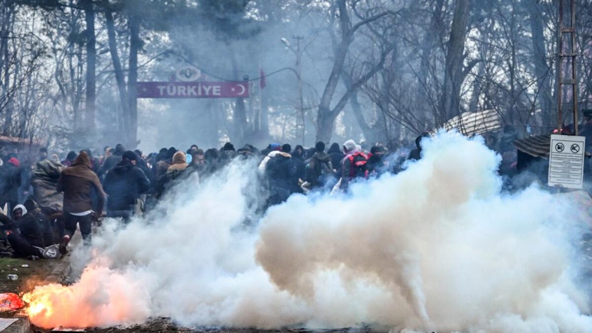 Migrants run away as Greek anti riot police officers use tears gas on the buffer zone Turkey-Greece border, at Pazarkule, in Edirne district, on February 29 , 2020. Thousands of migrants stuck on the Turkey-Greece border clashed with Greek police on February 29, 2020. Ozan KOSE / AFP