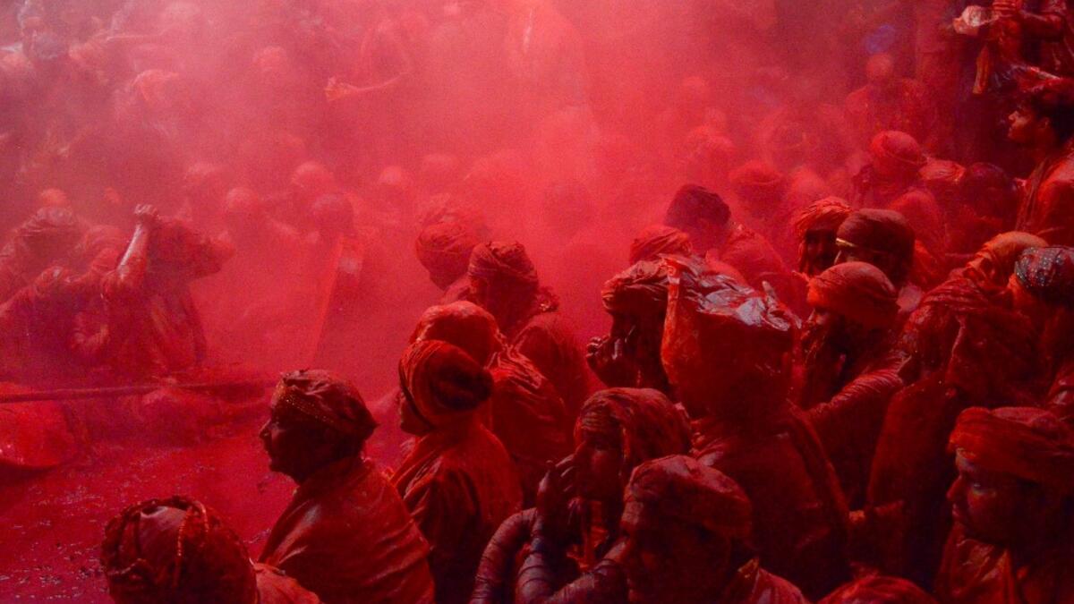 Coloured powder is thrown over villagers during the Lathmar Holi celebration in the village of Barsana on the outskirts of Mathura in the northern Indian state of Uttar Pradesh on March 4, 2020. Lathmar Holi is a local celebration of the Hindu festival of Holi, usually some days ahead of the Holi festival which is a spring festival, also called 'festival of colours' observed in India at the end of winter season. STR / AFP