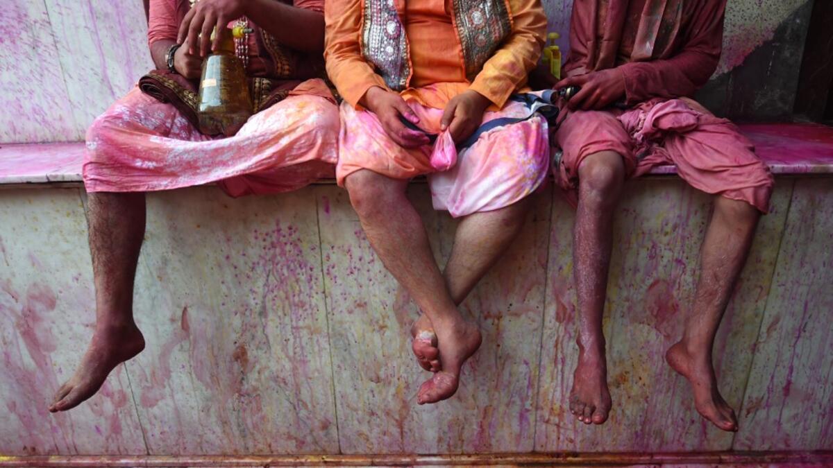 Hindu devotees sit in the column of a temple as they celebrate Holi, the spring festival of colours, during a traditional gathering at a temple in Nandgaon village in Uttar Pradesh state on March 5, 2020. Holi is observed in India at the end of the winter season on the last full moon of the lunar month. Money SHARMA / AFP