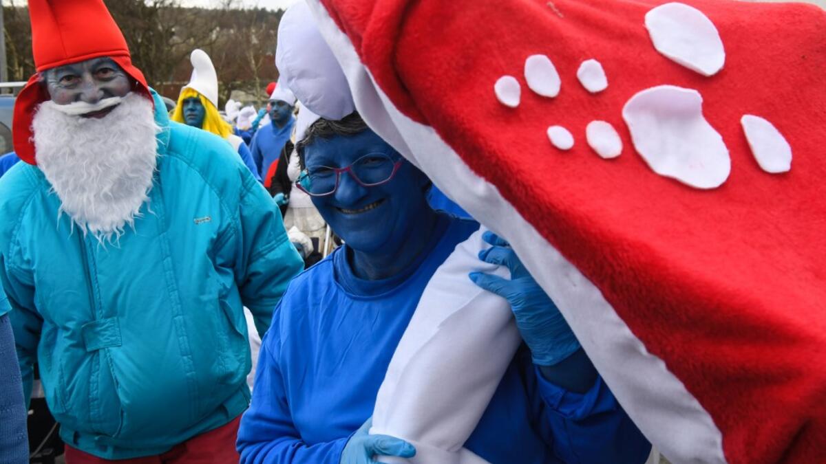 People dressed as Smurfs ('Schtroumpfs' in French), a Belgian comic franchise centered on a fictional colony of small, blue, human-like creatures who live in mushroom-shaped houses in the forest, pose for a picture as they attend a world record gathering of Smurfs on March 7, 2020, in Landerneau, western France. Damien MEYER / AFP