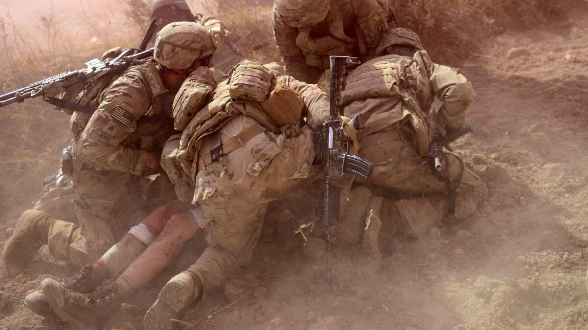 In this file photo taken on October 13, 2012, US Army soldiers attached to 2nd platoon, C troop, 1st Squadron (Airborne), 91st U.S Cavalry Regiment, 173rd Airborne Brigade Combat Team operating under NATO sponsored International Security Assistance Force (ISAF) protect a wounded comrade from dust and smoke flares after an Improvised Explosive Device (IED) blast during a patrol near Baraki Barak base in Logar Province. American forces have started pulling out of two bases in Afghanistan, a US official said o