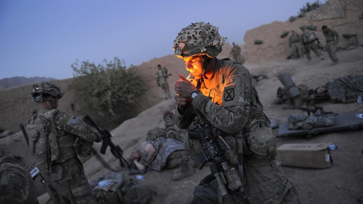 In this file photo taken on August 5, 2011, US soldier Specialist Joshua Schonert from 1st Platoon, Charlie Company, 2-87 Infantry, 3d Brigade Combat Team under Afghanistan's International Security Assistance Force (ISAF), lights a cigarette as he prepares for the day following earlier attacks by Taliban insurgents on their checkpoint in Kandalay village, Kandahar province southern Afghanistan. American forces have started pulling out of two bases in Afghanistan, a US official said on March 10, 2020 the day