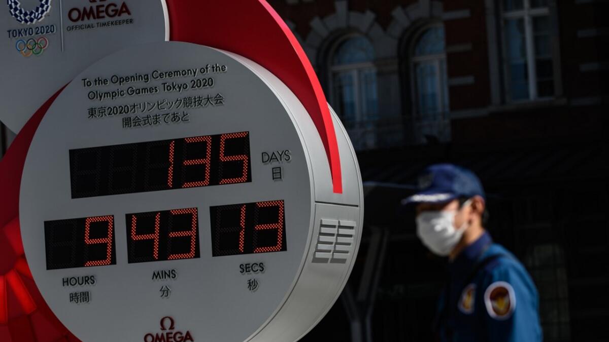 A security guard wearing a face mask walks in front of the Olympic countdown clock outside Tokyo station on March 11, 2020. Japan and Olympic organisers are at pains to insist this summer's Games in Tokyo are on, despite the new coronavirus outbreak. Philip FONG / AFP