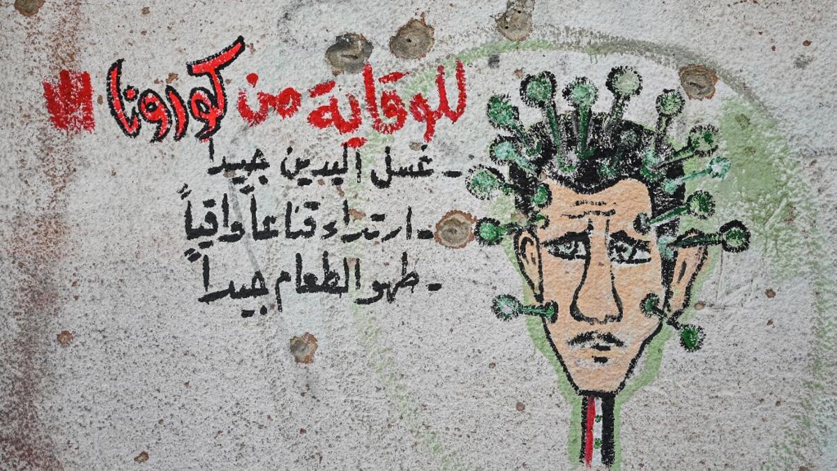 A graffiti portraying President Bashar al-Assad as the coronavirus is seen on the wall of a destroyed school in Binnish town in Syria’s northwestern Idlib province near the Turkish border, on March 10, 2020. Ozan KOSE / AFP