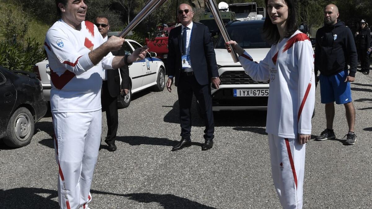 European Commission vice-president in charge for promoting our European way of life Margaritis Schinas (L) holds the Olympic flame during the flame lighting ceremony on March 12, 2020 in ancient Olympia, ahead of the Tokyo 2020 Olympic Games. LOUISA GOULIAMAKI / AFP