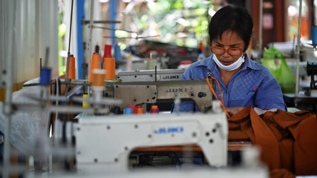 A Buddhist devotee sews face masks made from fabric derived from recycled plastic bottles, amid concerns over the spread of the COVID-19 coronavirus, at Wat Chak Daeng Buddhist temple in Samut Prakan on March 23, 2020. The plastic wastes are sent to a separate recycling facility processing it into thread materials and woven as special fabric for monks. Lillian SUWANRUMPHA / AFP