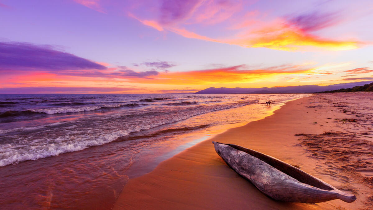 Lake Malawi sunset in Kande beach Africa, canoe boat on beach peaceful beach holiday beautiful sunset colors blue purple orange yellow in sky and clouds (Shutterstock)
