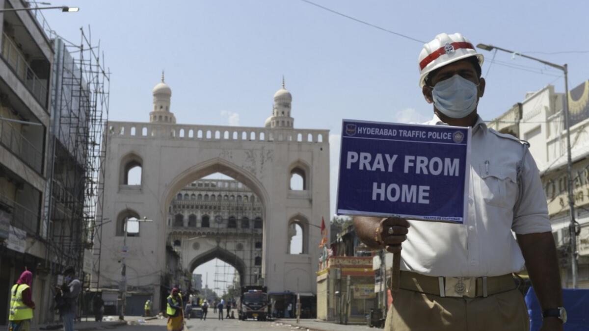 A traffic police personnel holds a placard on a deserted road during a one-day nationwide Janata (civil) curfew imposed as a preventive measure against the COVID-19 coronavirus, in Hyderabad on March 22, 2020. Nearly one billion people around the world were confined to their homes, as the coronavirus death toll crossed 13,000 and factories were shut in worst-hit Italy after another single-day fatalities record. NOAH SEELAM / AFP