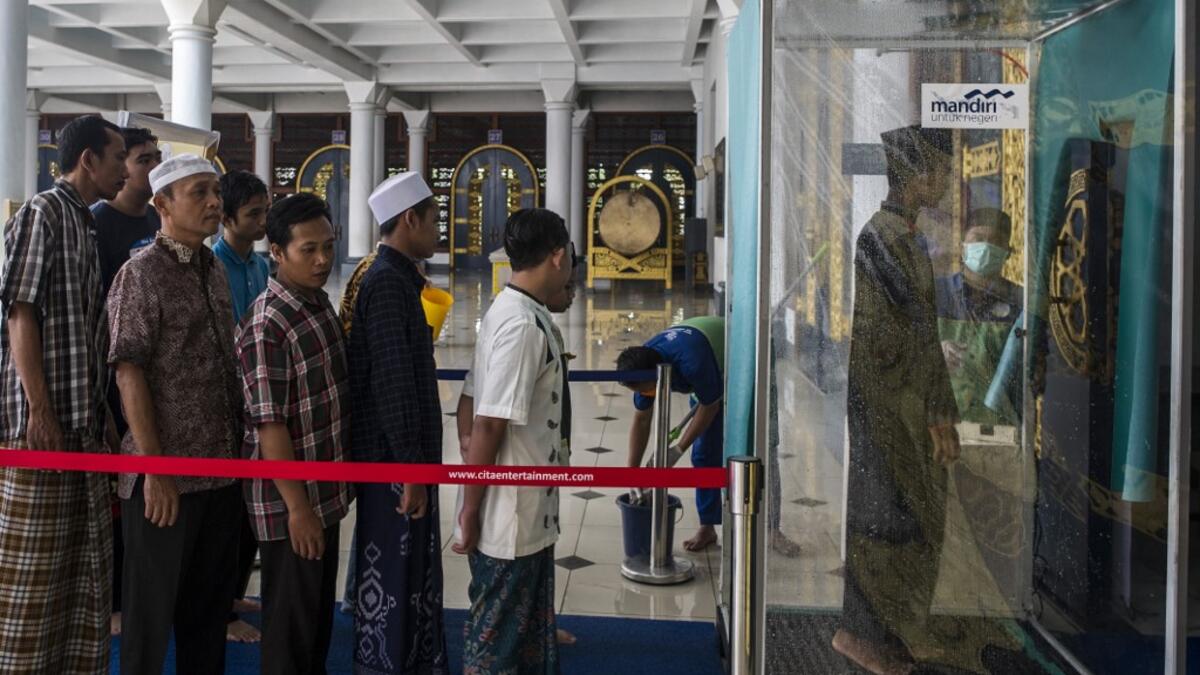 Indonesians walk through a disinfectant chamber before entering a mosque during Friday prayers in Surabaya, East Java on March 27, 2020, as a measure to stop the spread of the COVID-19 coronavirus. JUNI KRISWANTO / AFP