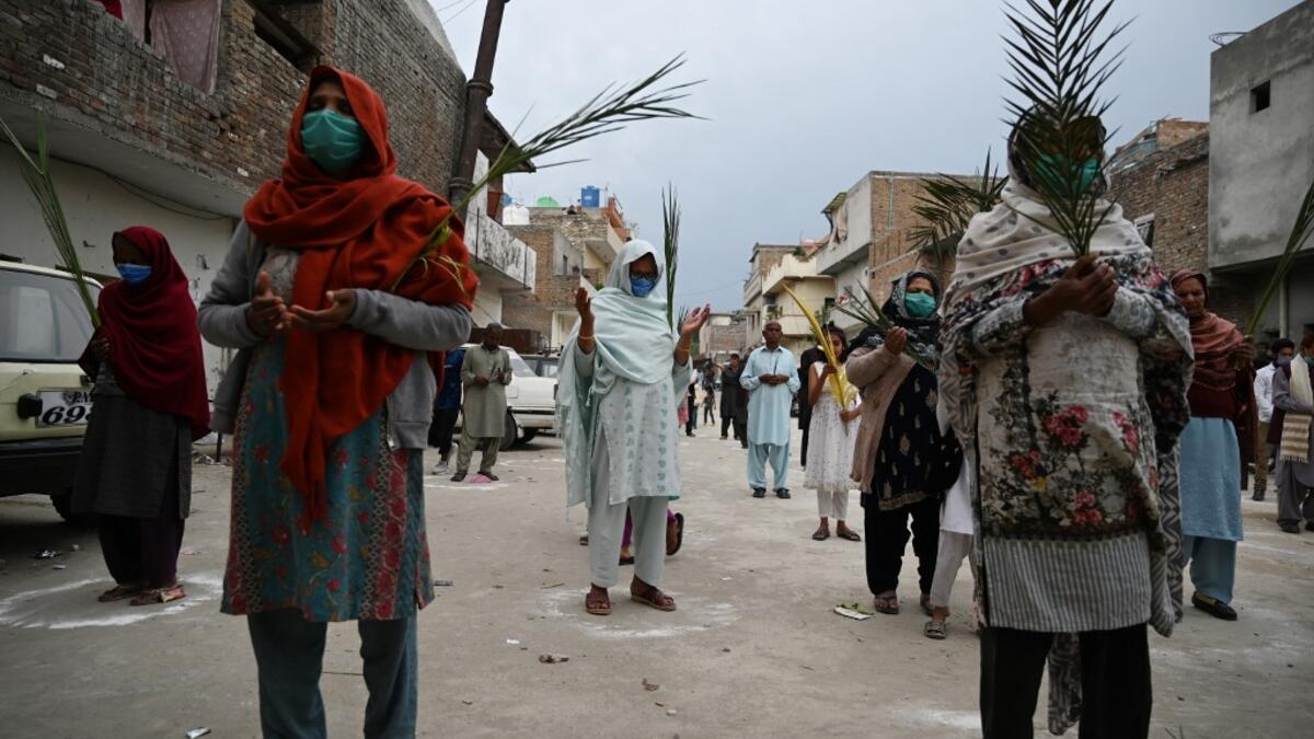 Christian devotees stand in circles marked on the ground to maintain social distancing as they hold palm branches to celebrate a Palm Sunday service at the Christian neighborhood during a government-imposed nationwide lockdown as a preventive measure against the COVID-19 coronavirus, in Islamabad on April 5, 2020.  Aamir QURESHI / AFP