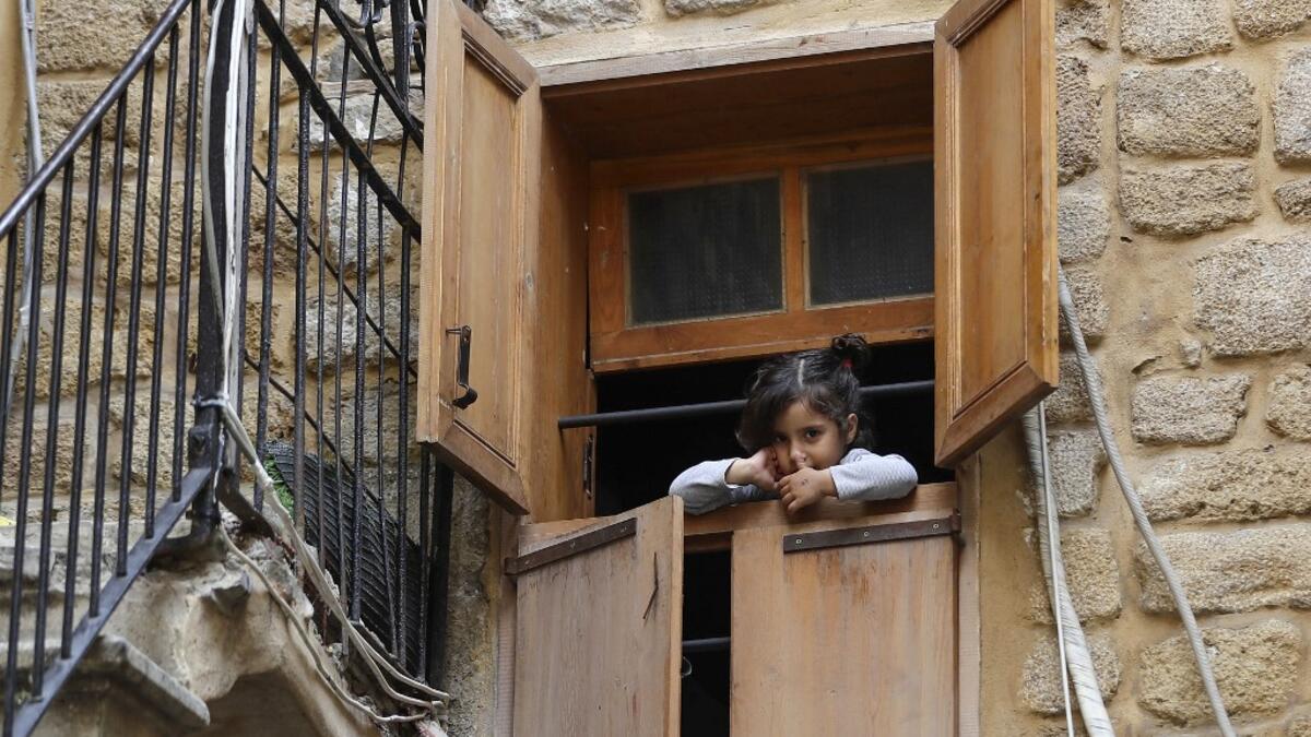 A Lebanese girl looks out of a window during confinement at home due to the COVID-19 pandemic, in the historic part of the southern coastal city of Sidon (Saida), on April 6, 2020. Lebanon's President called on international donors to provide financial assistance to the crisis-hit country as it grapples with a severe economic downturn compounded by the novel coronavirus pandemic. JOSEPH EID / AFP