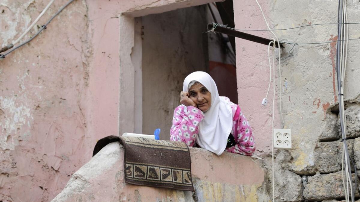 A Lebanese woman sits at her home's entrance during confinement due to the COVID-19 pandemic, in the historic part of the southern coastal city of Sidon (Saida), on April 6, 2020. Lebanon's President called on international donors to provide financial assistance to the crisis-hit country as it grapples with a severe economic downturn compounded by the novel coronavirus pandemic. JOSEPH EID / AFP