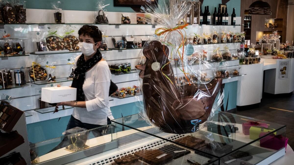 A client with a face mask leaves the shop of pastry and chocolate maker Didier Girard after buying Easter chocolates in Vourles, near Lyon at on April 7, 2020, on the twenty-second day of a strict lockdown in France to stop the spread of COVID-19, caused by the novel coronavirus. JEAN-PHILIPPE KSIAZEK / AFP