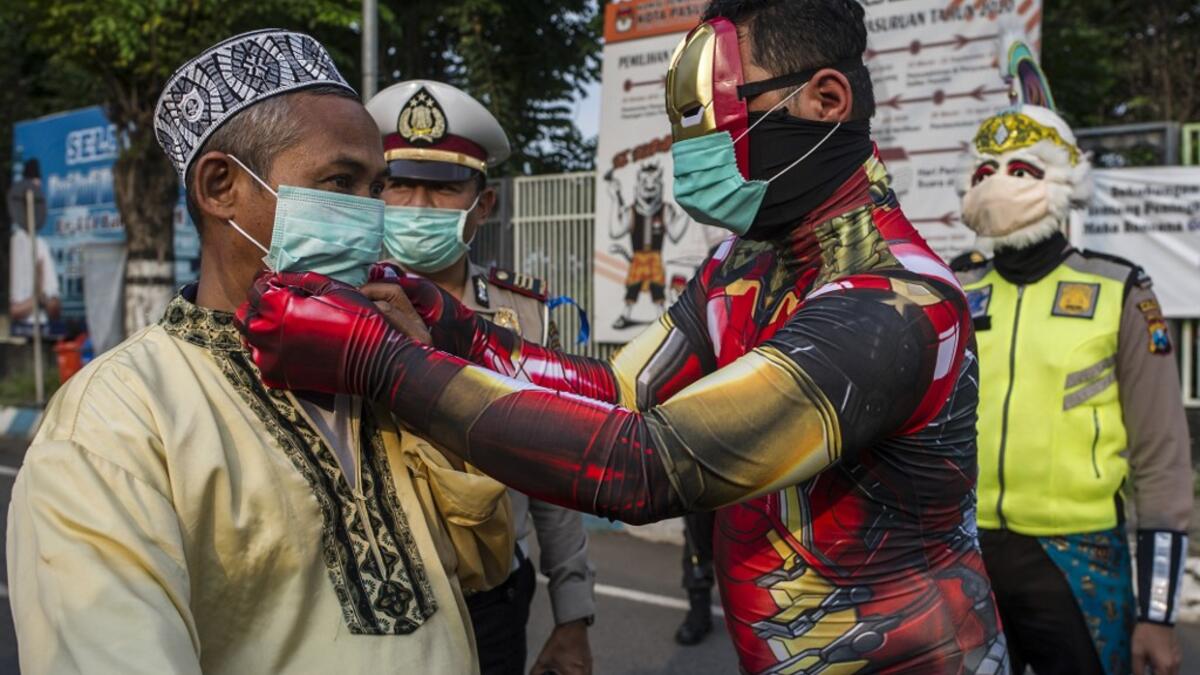 Indonesian police officers wearing Indonesian superhero costumes on the street adjusts a face mask in Pasuruan, East Java on April 9, 2020, amid concert to the COVID-19 coronavirus. JUNI KRISWANTO / AFP