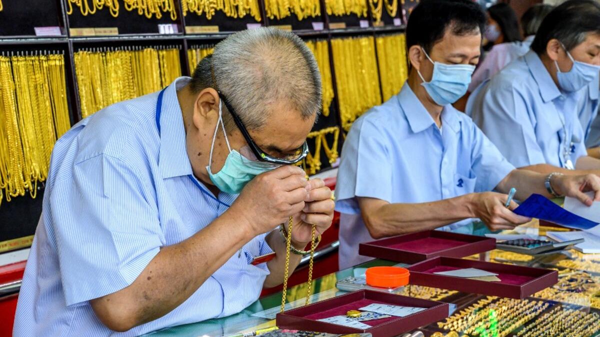 An employee checks a gold chain offered for sale in a gold shop in Bangkok's Chinatown on April 15, 2020. Hundreds of Bangkok residents rushed to goldsmith shops in order to sell their jewelries as gold prices reached its highest levels since 2012. Mladen ANTONOV / AFP
