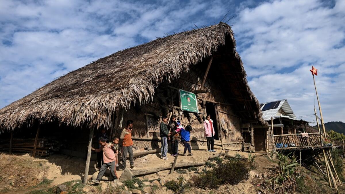 This photo taken on February 9, 2020 shows people standing outside a Union Solidarity and Development Party house in Karmawlawyi village in Myanmar's Sagaing region, near the border with India. The king of the Konyak tribe sleeps in Myanmar, but eats in India -- his house, village and people divided by a mountain border which serves as a vulnerable lifeline now severed by a coronavirus lockdown.  Ye Aung THU / AFP