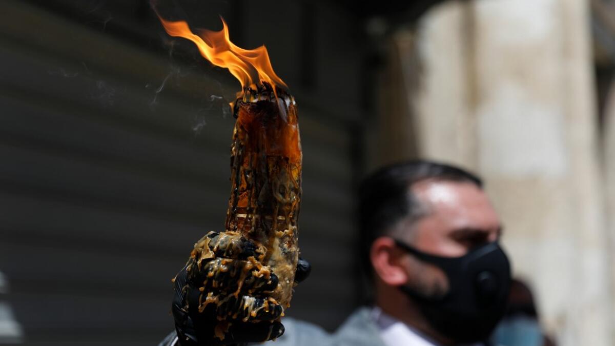 A man wearing a protective mask holds up candles lit from the Holy Fire in the church of the Holy Sepulchre, as very few Orthodox Christians gather in Jerusalem's Old City to celebrate Easter due to the lockdown imposed by authorities in a bid to limit the spread of the novel coronavirus, on April 18, 2020. Ahmad GHARABLI / AFP