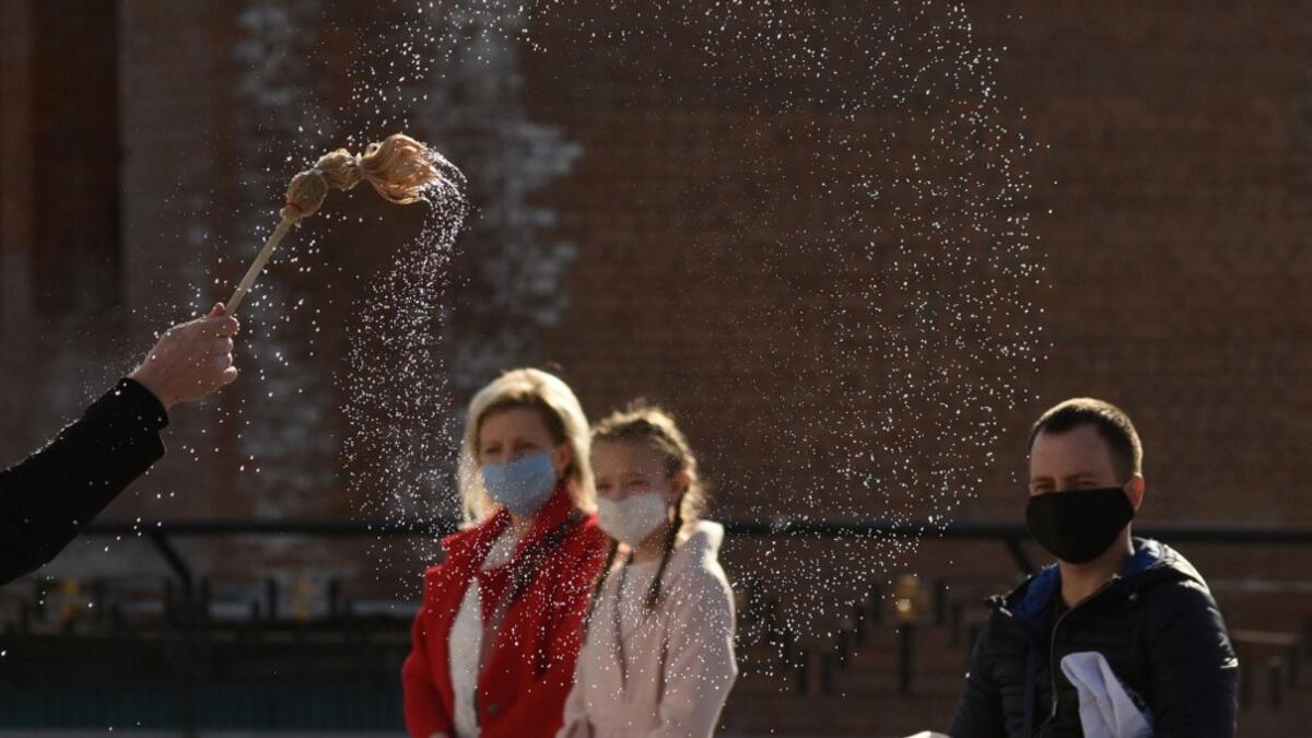 A priest of the Greek Catholic Church blesses believers wearing face masks as they keep social distance during the celebration of Orthodox Easter outside the Church of the Nativity of the Blessed Virgin, in western Ukrainian city of Lviv, on April 18, 2020, amid the COVID-19 pandemic caused by the novel coronavirus. Yuri DYACHYSHYN / AFP