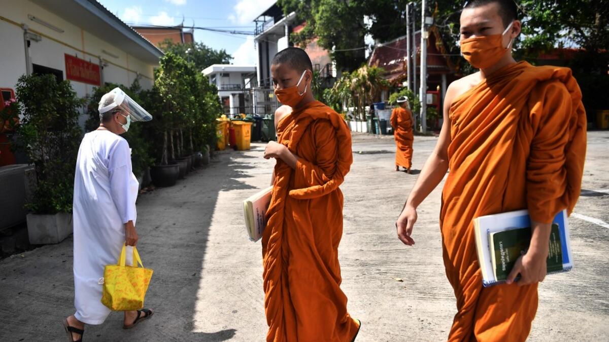 Novice monks wearing masks as a preventive measure against the spread of the COVID-19 coronavirus walk around after religious studies at Wat Molilokkayaram Buddhist temple in Bangkok on April 20, 2020. Lillian SUWANRUMPHA / AFP