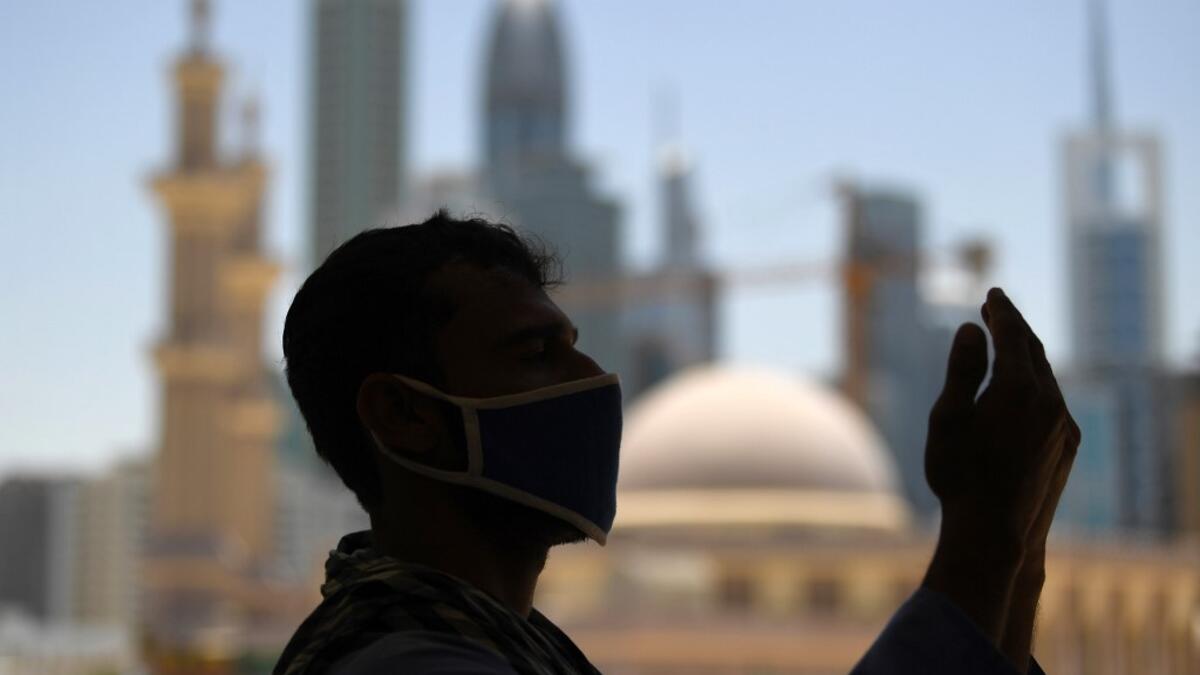 A mask-clad Muslim worker prays near a mosque on the first Friday of the holy fasting month of Ramadan, amidst a curfew due to the COVID-19 coronavirus pandemic, in Dubai on April 24, 2020. KARIM SAHIB / AFP
