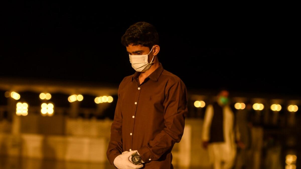 A Muslim wearing facemask and gloves offers a special 'Taraweeh' evening prayer ahead of the first day of the Muslim holy month of Ramadan at the Grand Faisal Mosque in Islamabad on April 24, 2020.  Aamir QURESHI / AFP