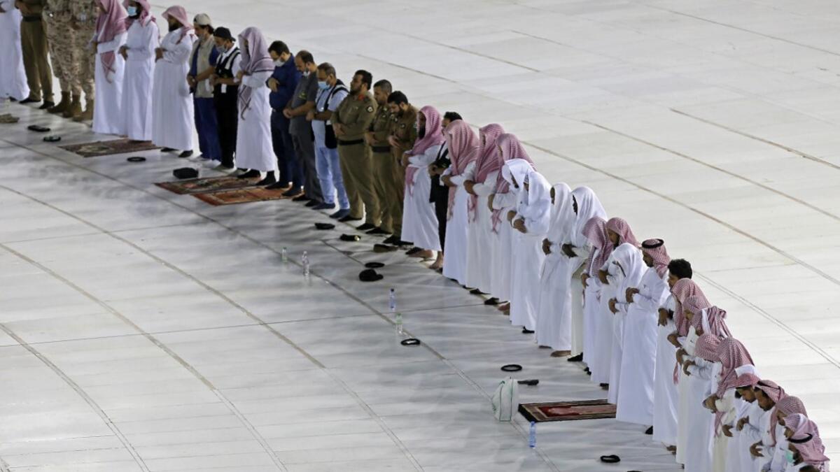 A picture taken on April 24, 2020, shows Saudi men performing prayers next to the Kaaba in Mecca's Grand Mosque, Islam's holiest site, on the first day of the Islamic holy month of Ramadan, amid unprecedented bans on family gatherings and mass prayers due to the coronavirus (COVID-19) pandemic. STR / AFP
