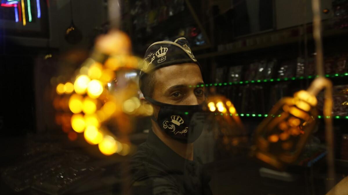 A Palestinian worker at a desserts shop wipes the surface of its window while clad in a face mask, a precaution due to the COVID-19 coronavirus pandemic, in Rafah in the southern Gaza Strip on the second night of the Muslim holy month of Ramadan early on April 25, 2020, as people shop for supplies at the start of the holy month. SAID KHATIB / AFP
