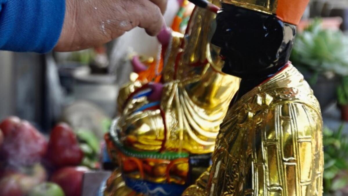 In this picture taken on March 17, 2020, sculptor Lin Hsin-lai paints a Taoist god statue during a ceremony at his workplace in Taoyuan, northern Taiwan. Every spare surface of Lin Hsin-lai's four-storey shop is crammed with a pantheon of Taiwan's celestial beings, testament to the decades he has spent sheltering and restoring unwanted statues of gods.  Sam Yeh / AFP