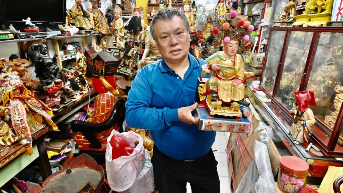 In this picture taken on March 17, 2020, sculptor Lin Hsin-lai displays a Taoist god statue at his workplace in Taoyuan, northern Taiwan. Every spare surface of Lin Hsin-lai's four-storey shop is crammed with a pantheon of Taiwan's celestial beings, testament to the decades he has spent sheltering and restoring unwanted statues of gods.  Sam Yeh / AFP