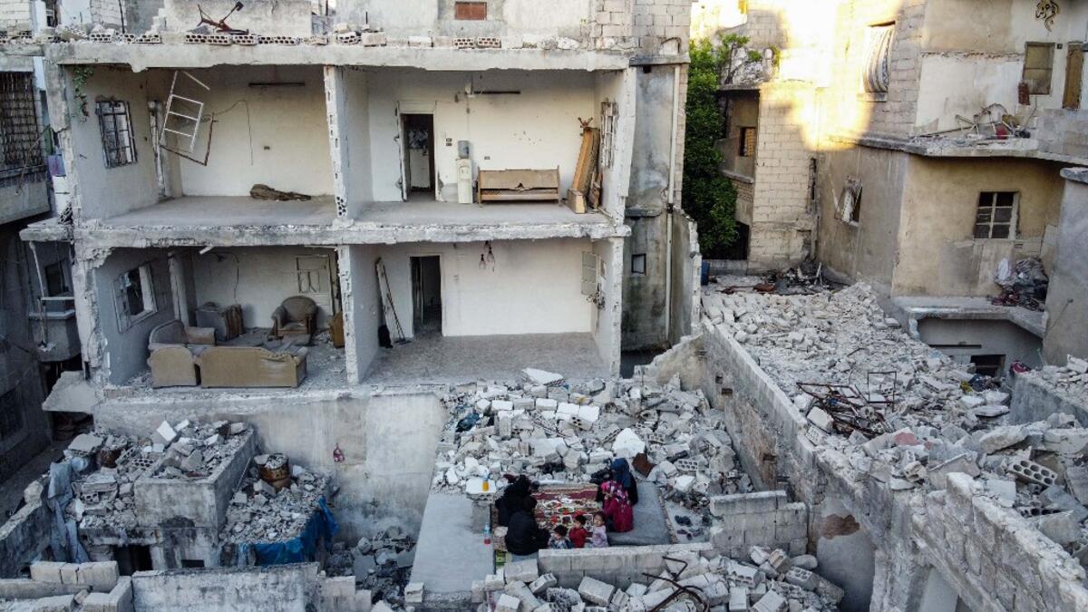 This picture taken on May 4, 2020 during the Muslim holy fasting month of Ramadan shows members of the displaced Syrian family of Tareq Abu Ziad, from the town of Ariha in the southern countryside of the Idlib province, breaking their fast together for the sunset "iftar" meal, in the midst of the rubble of their destroyed home upon their return to the town for one day after fleeing during the previous military assault by Syrian government forces and their allies. AAREF WATAD / AFP