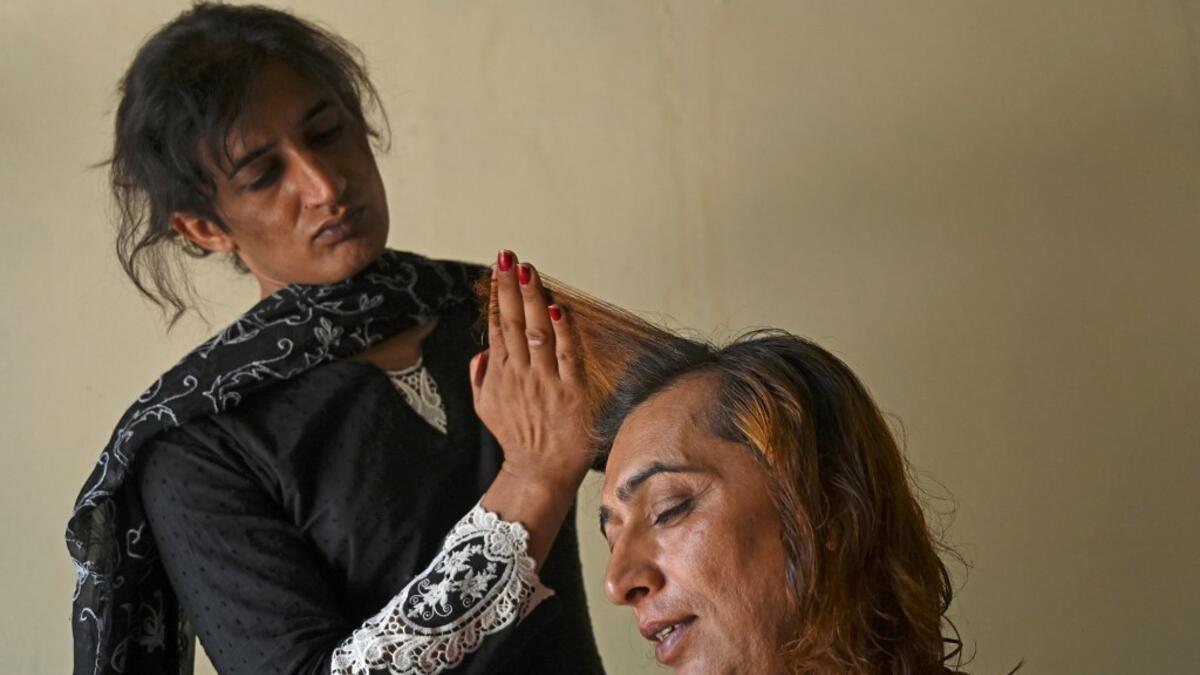 In this picture taken on May 10, 2020, Julie Khan (L), a member of the transgender community, cuts the hair of Nadeem Kashish at a shelter house in the Bari Imam neighbourhood of Islamabad. Transgender people in the country are known as "khawajasiras" or "hijras" -- an umbrella term denoting a third sex that includes transgender women and cross-dressers. Pakistan became one of the first countries in the world to legally recognise a third sex in 2009 and began issuing transgender passports from 2017. Aamir Q