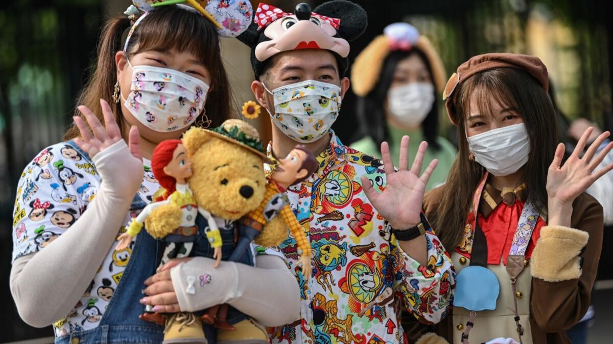 People wearing face masks wait to enter the Disneyland amusement park in Shanghai on May 11, 2020. Disneyland Shanghai reopened on May 11 to the public after being closed since January due to the COVID-19 coronavirus outbreak. Hector RETAMAL / AFP