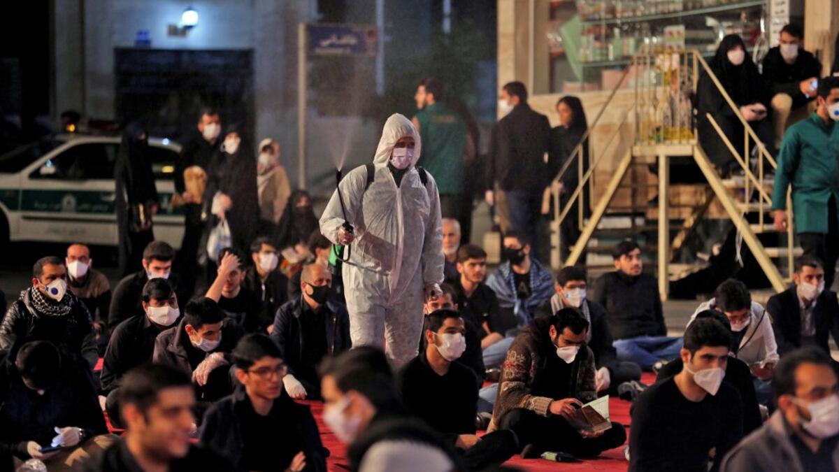 Iranians, some wearing face masks against the Covid-19 coronavirus, attend Laylat al-Qadr prayers, one of the holiest nights during the Muslim fasting month of Ramadan, outside a mosque in the Tehran, on May 13, 2020. ATTA KENARE / AFP