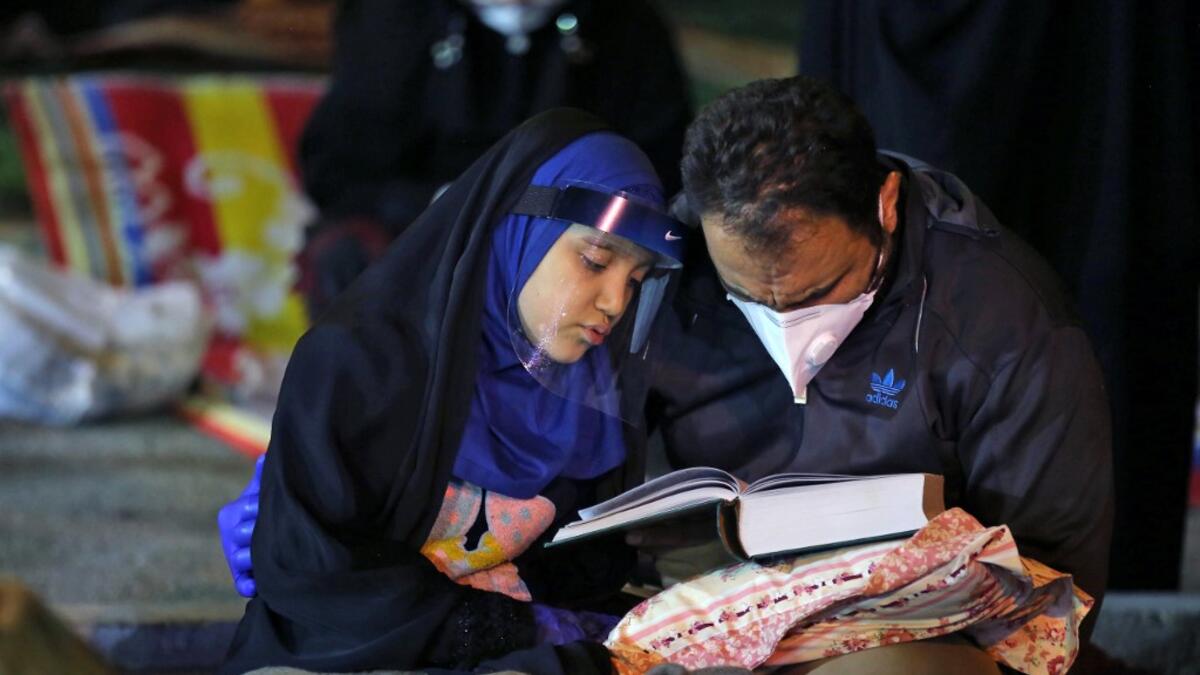 Iranians wearing face masks against the Covid-19 coronavirus attend Laylat al-Qadr prayers, one of the holiest nights during the Muslim fasting month of Ramadan, outside a mosque in the Tehran, on May 13, 2020. ATTA KENARE / AFP