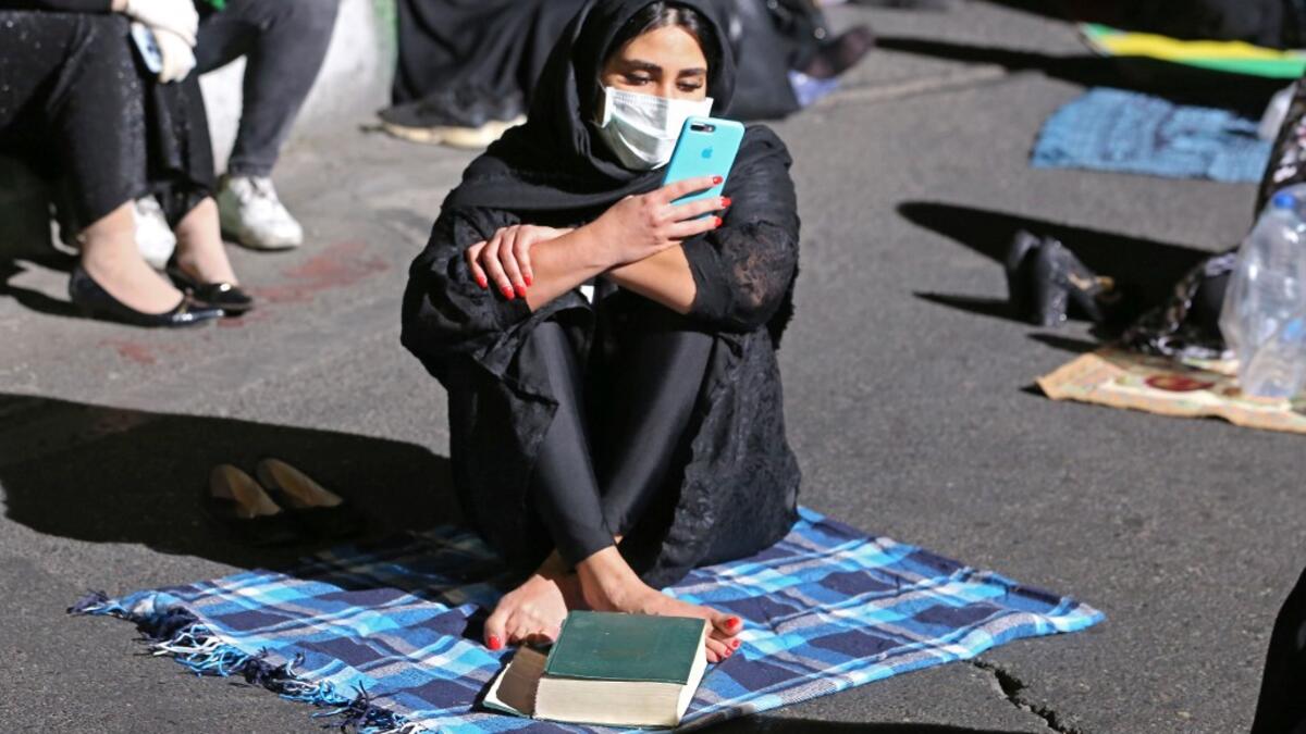 An Iranian woman wearing a face mask against the Covid-19 coronavirus attends Laylat al-Qadr prayers, one of the holiest nights during the Muslim fasting month of Ramadan, outside a mosque in the Tehran, on May 13, 2020. ATTA KENARE / AFP